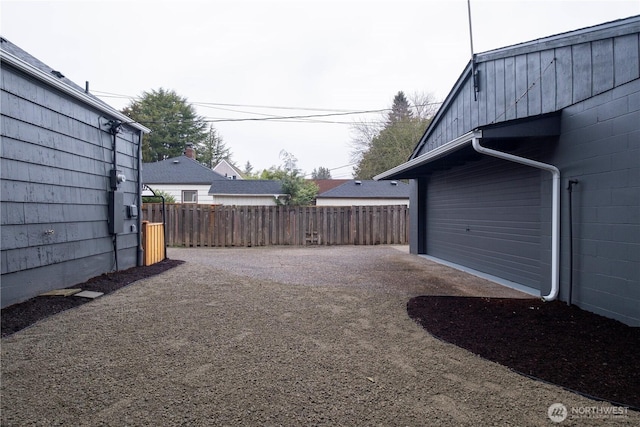 view of yard with a garage, driveway, and fence