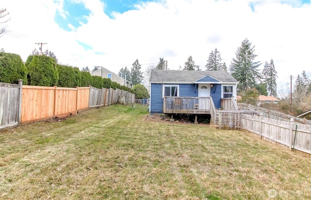 back of property with a fenced backyard, a wooden deck, and a yard