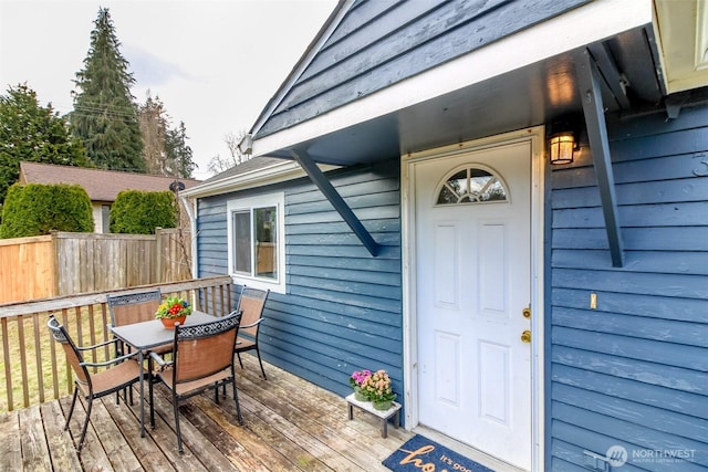 property entrance with outdoor dining area, fence, and a deck