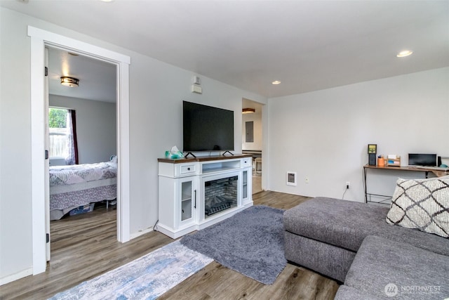 living room featuring baseboards, visible vents, wood finished floors, a fireplace, and recessed lighting