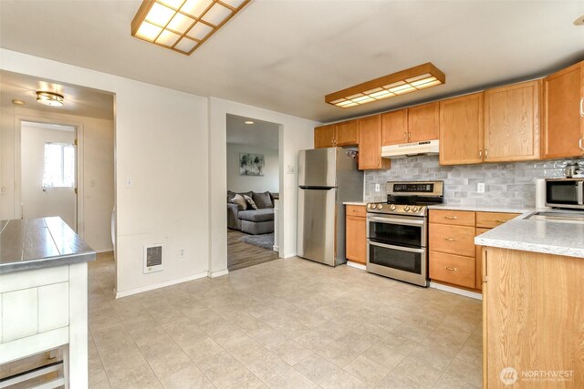 kitchen featuring visible vents, appliances with stainless steel finishes, light countertops, under cabinet range hood, and backsplash