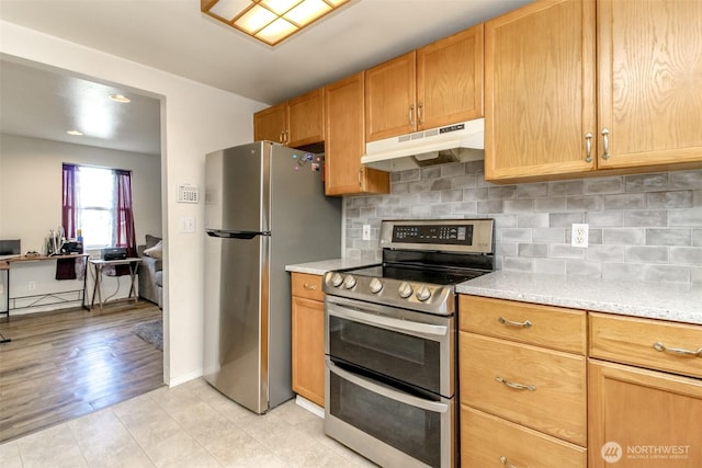 kitchen featuring light stone counters, light tile patterned floors, backsplash, appliances with stainless steel finishes, and under cabinet range hood