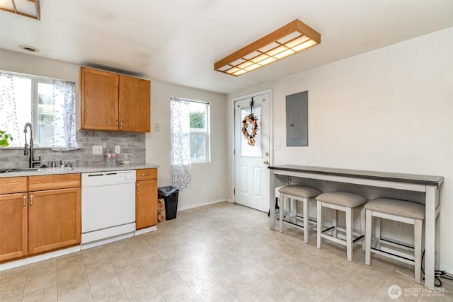 kitchen with tasteful backsplash, light countertops, a sink, electric panel, and dishwasher