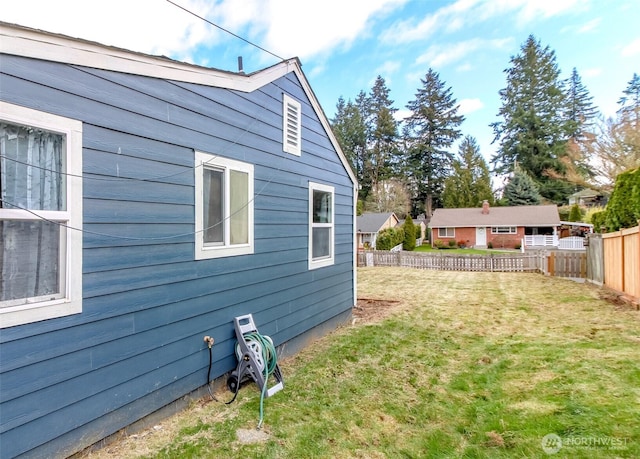 view of property exterior with fence and a lawn