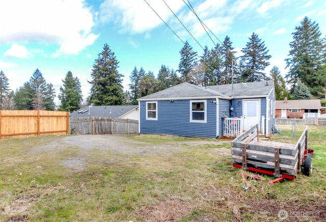 rear view of property featuring a fenced backyard and a lawn