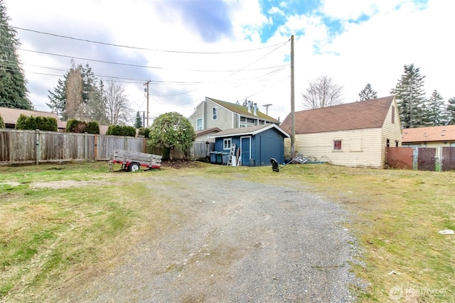 exterior space featuring driveway, a shed, an outdoor structure, and fence