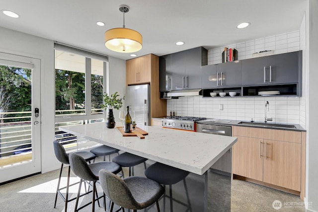 kitchen featuring under cabinet range hood, tasteful backsplash, appliances with stainless steel finishes, and a sink