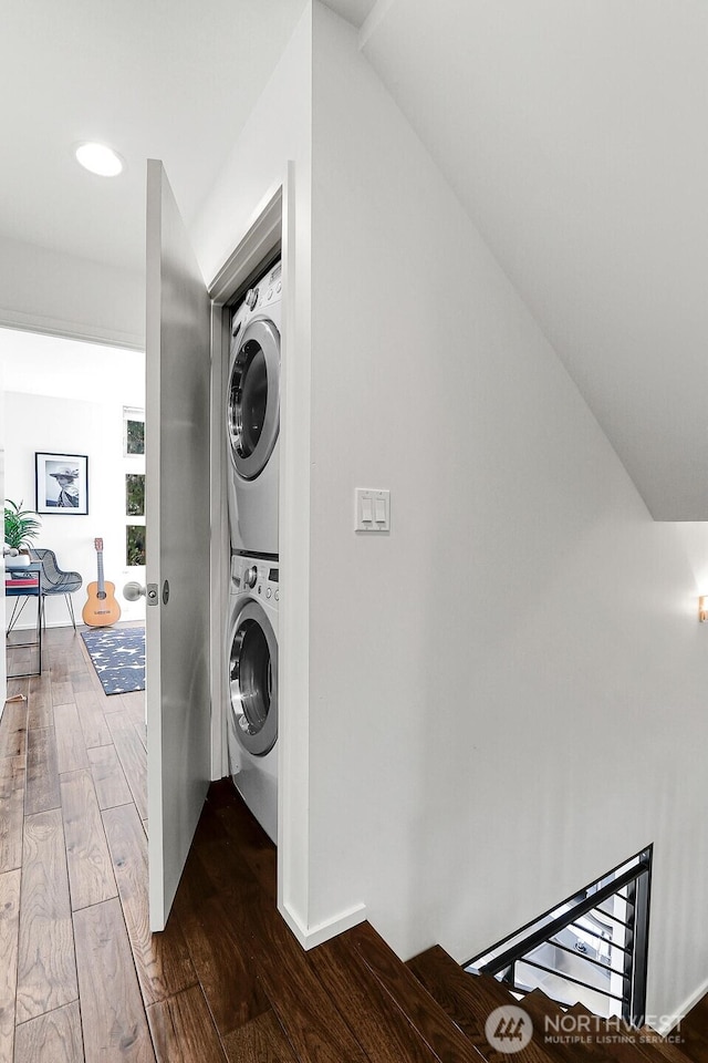 washroom featuring laundry area, stacked washer / drying machine, and wood finished floors