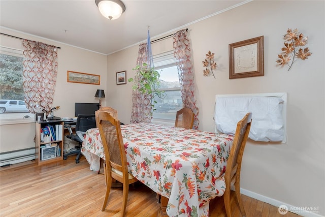 dining space with a baseboard heating unit, crown molding, baseboards, and wood finished floors