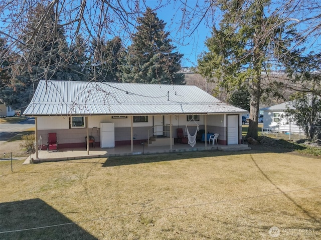 rear view of house featuring metal roof, a lawn, and a patio area