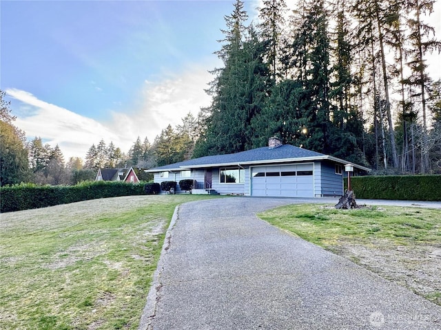 ranch-style home with an attached garage, a chimney, aphalt driveway, and a front yard