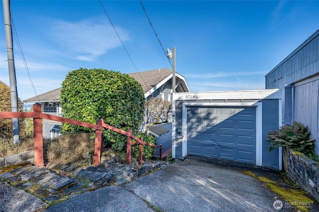 garage featuring driveway and fence