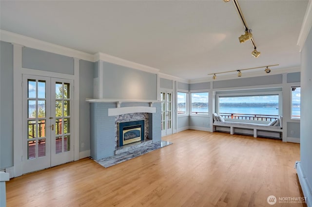 unfurnished living room with a glass covered fireplace, wood finished floors, french doors, and a baseboard radiator