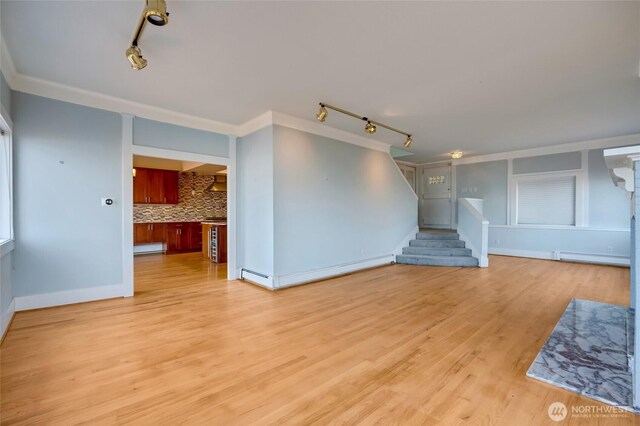 unfurnished living room featuring stairway, ornamental molding, light wood-style floors, and a baseboard radiator