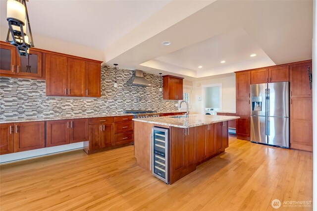 kitchen featuring beverage cooler, light wood-style flooring, stainless steel fridge with ice dispenser, a sink, and a raised ceiling