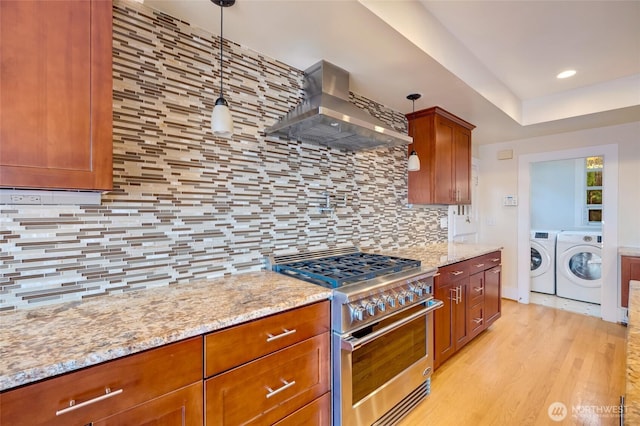 kitchen featuring high end range, light stone counters, light wood finished floors, separate washer and dryer, and wall chimney range hood