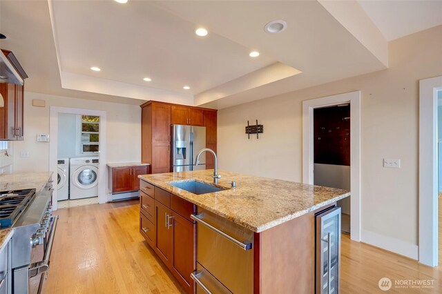 kitchen with washer and clothes dryer, appliances with stainless steel finishes, a raised ceiling, and a sink