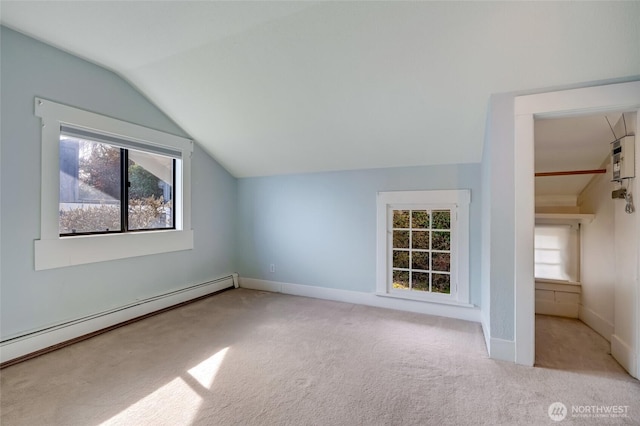 additional living space with a baseboard heating unit, lofted ceiling, carpet, and baseboards