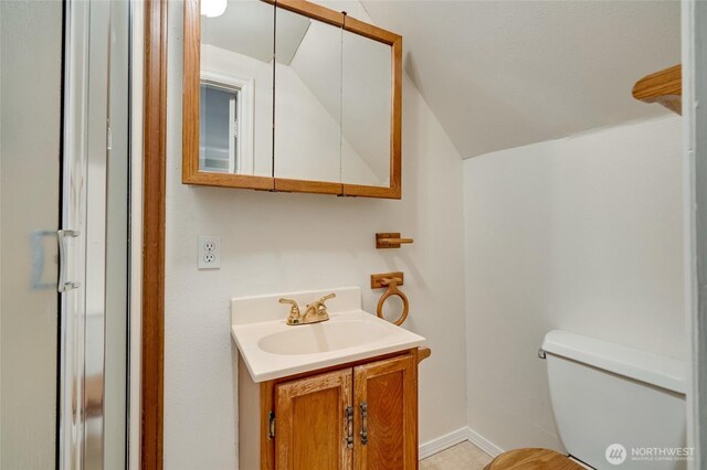 bathroom with baseboards, toilet, vanity, and vaulted ceiling