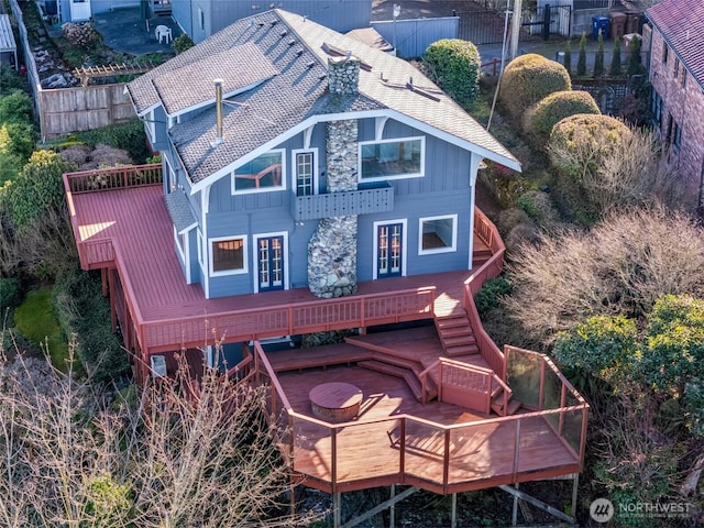 rear view of property with a deck, board and batten siding, french doors, and fence