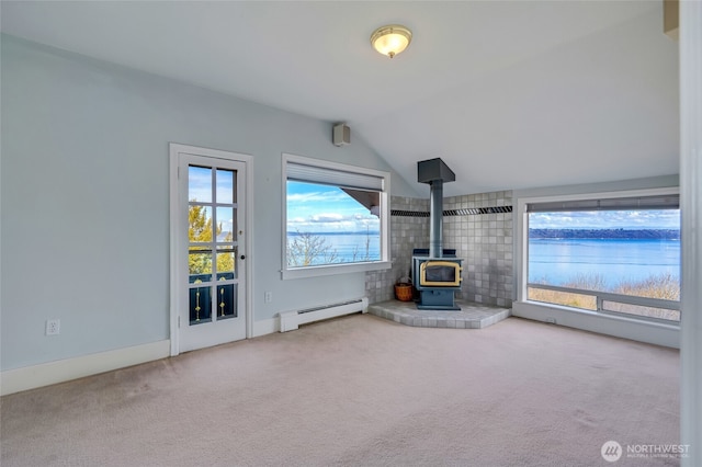 unfurnished living room with vaulted ceiling, carpet flooring, a wood stove, and a baseboard radiator