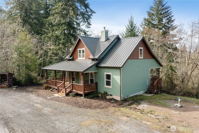 chalet / cabin featuring metal roof, a porch, dirt driveway, a standing seam roof, and a chimney