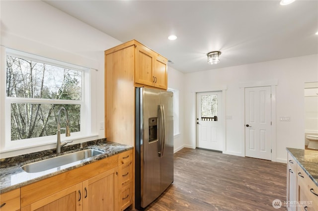 kitchen with dark stone counters, plenty of natural light, a sink, and stainless steel fridge with ice dispenser