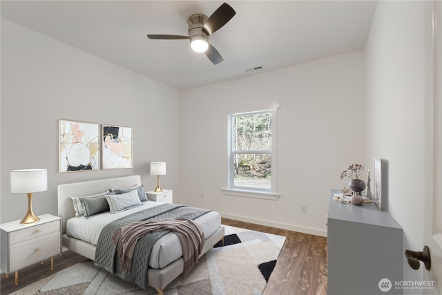 bedroom with baseboards, visible vents, ceiling fan, and wood finished floors