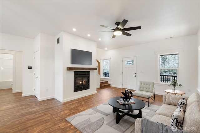 living room featuring baseboards, wood finished floors, a glass covered fireplace, and recessed lighting