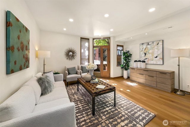 living area with baseboards, light wood-type flooring, visible vents, and recessed lighting