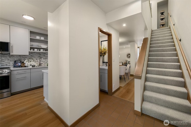 interior space with open shelves, stainless steel appliances, light countertops, decorative backsplash, and white cabinetry