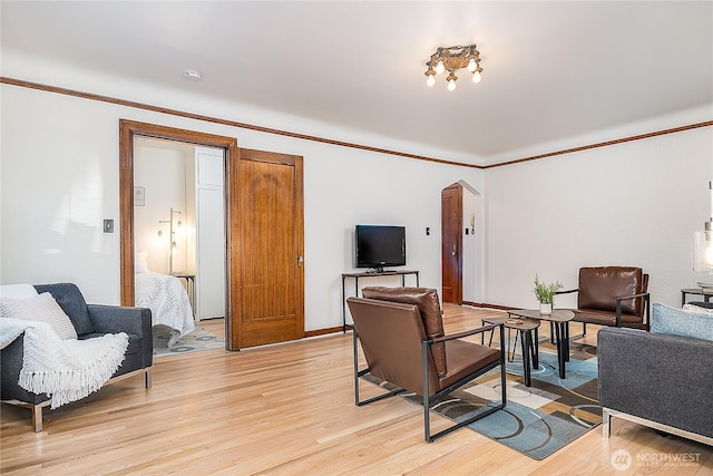 living room featuring crown molding, light wood-style flooring, and baseboards