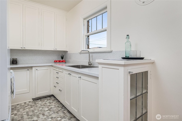 kitchen with light countertops, a sink, decorative backsplash, and white cabinetry