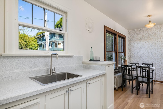 kitchen featuring radiator, wallpapered walls, light countertops, and a sink