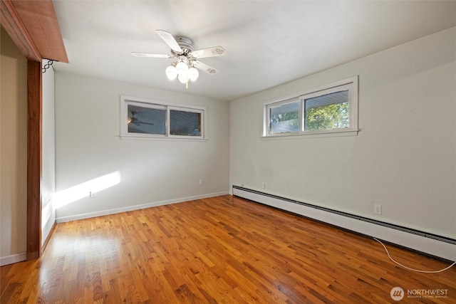 spare room featuring a baseboard heating unit, baseboards, a ceiling fan, and light wood-style floors