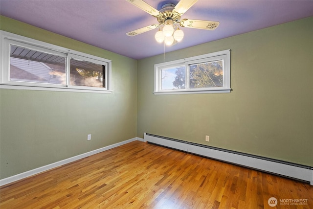 empty room featuring ceiling fan, a baseboard radiator, wood finished floors, and baseboards