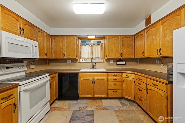 kitchen featuring white appliances, brown cabinets, a sink, and stone finish flooring