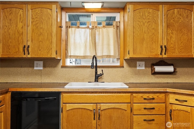 kitchen featuring brown cabinets, black dishwasher, backsplash, and a sink