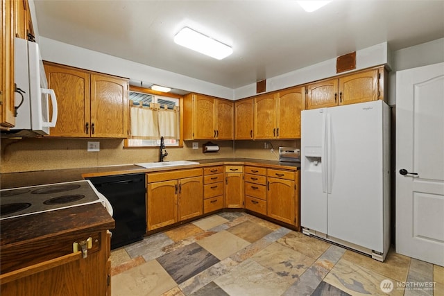 kitchen featuring brown cabinetry, white appliances, a sink, and stone finish flooring