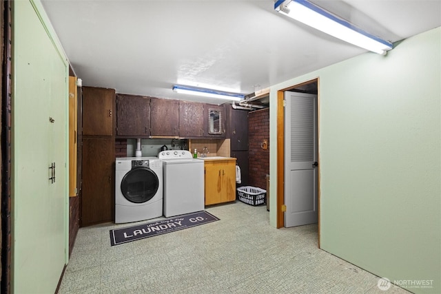 laundry room featuring washing machine and dryer, cabinet space, and a sink