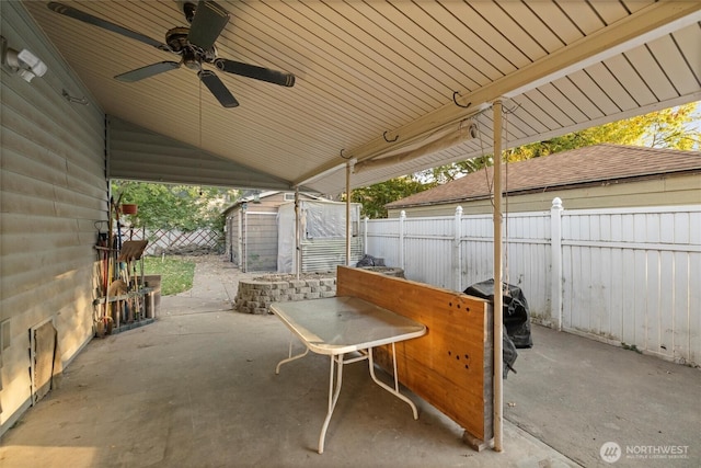 view of patio featuring a fenced backyard, a storage unit, ceiling fan, and an outdoor structure