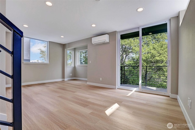 unfurnished room featuring light wood-style floors, recessed lighting, an AC wall unit, and baseboards