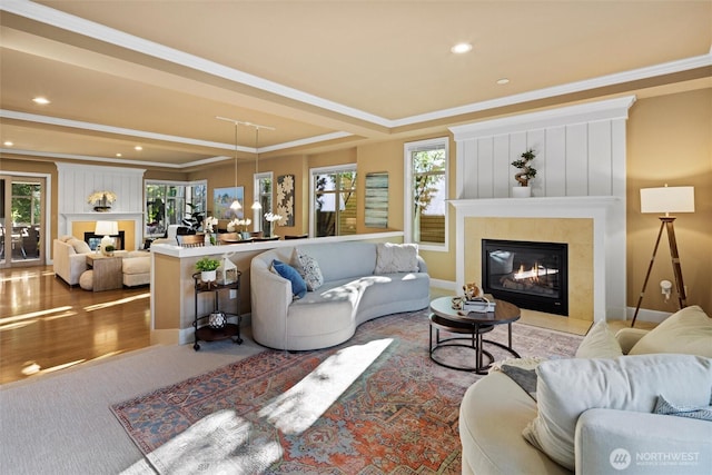 living room featuring ornamental molding, wood finished floors, plenty of natural light, and a glass covered fireplace