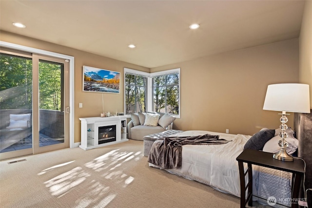 carpeted bedroom featuring access to exterior, a glass covered fireplace, visible vents, and recessed lighting