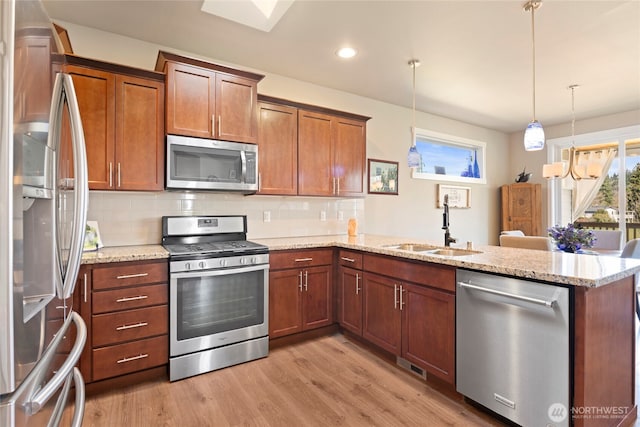 kitchen with tasteful backsplash, a peninsula, stainless steel appliances, light wood-type flooring, and a sink