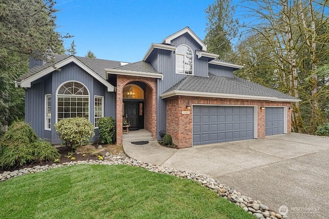 tri-level home featuring a front lawn, driveway, a shingled roof, a garage, and brick siding