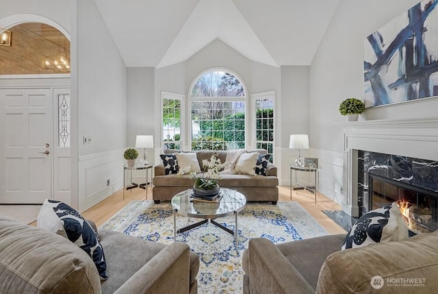 living room with vaulted ceiling, wood finished floors, a high end fireplace, and wainscoting