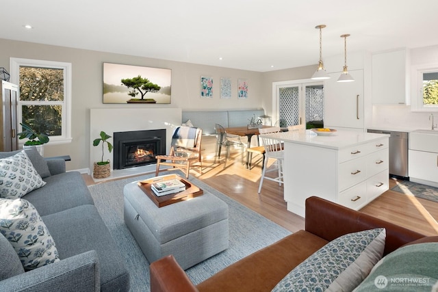 living room featuring recessed lighting, a glass covered fireplace, and light wood-style floors