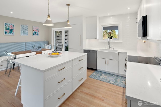 kitchen featuring light wood-style floors, a sink, stainless steel dishwasher, and black electric cooktop