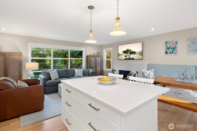 kitchen with light countertops, open floor plan, white cabinets, and light wood-style flooring